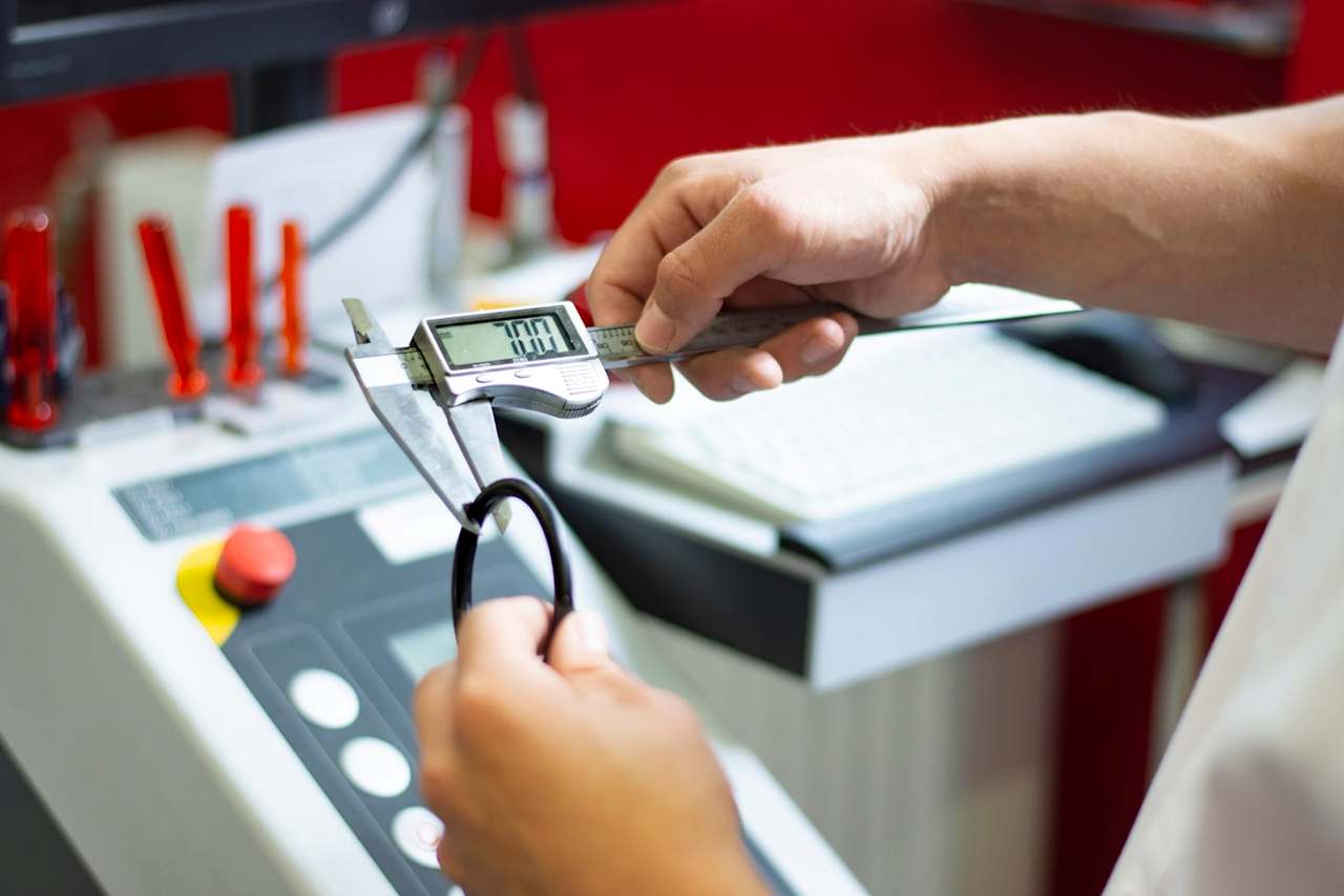 Hands measuring a ring-shaped part with a digital caliper