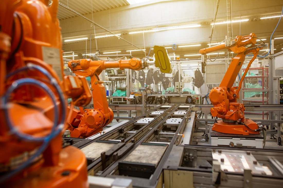 Orange robot arms beside a conveyor on an automated factory production line